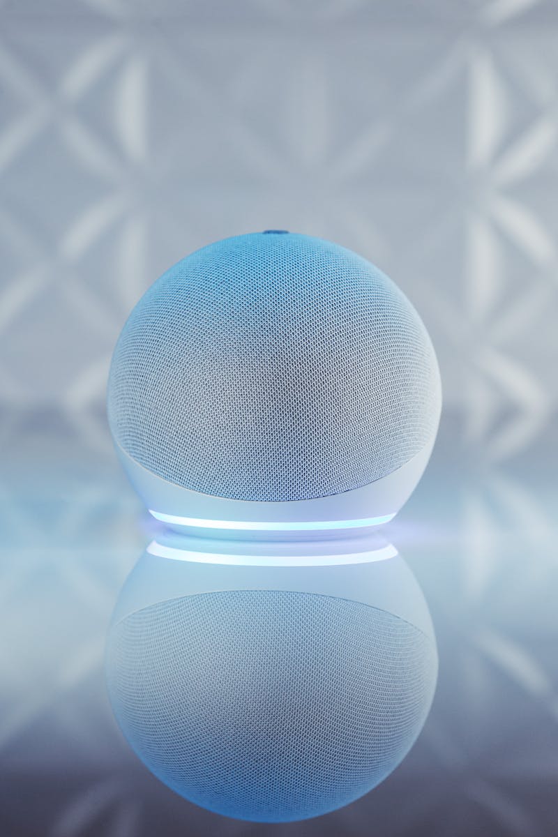 Close-up of an illuminated smart speaker with a reflective surface, showcasing modern technology.